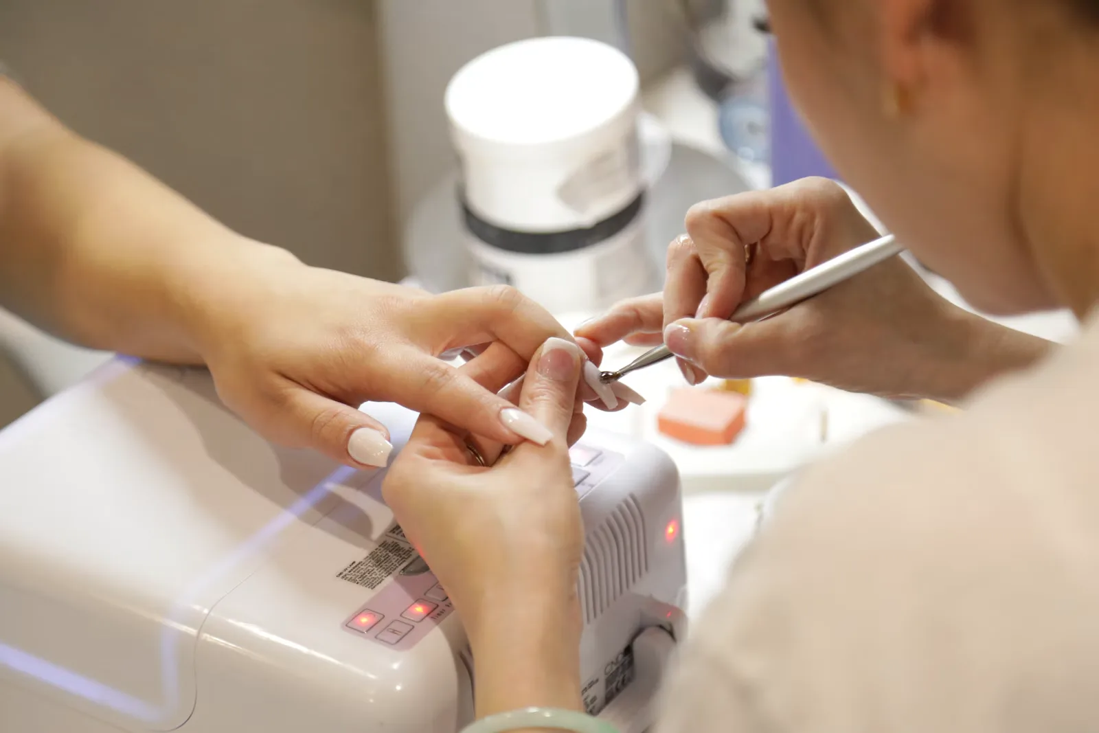 Nail technician working on a client's fingertips at a salon table