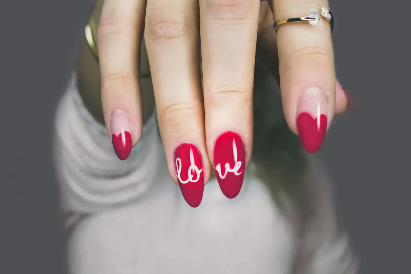 Hand with red nails, two painted with the word love in white lettering
